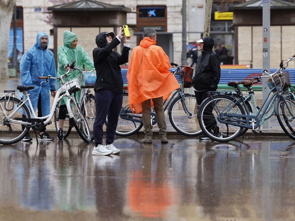 Foto: Varias personas se protegen de la lluvia con chubasqueros. (EFE/Ana Escobar)