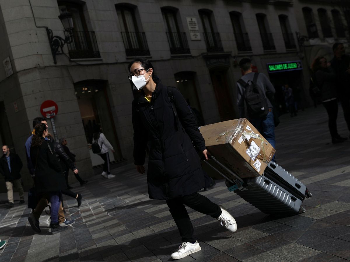 Foto: Una mujer con mascarilla arrastra su maleta en Madrid. (Reuters)