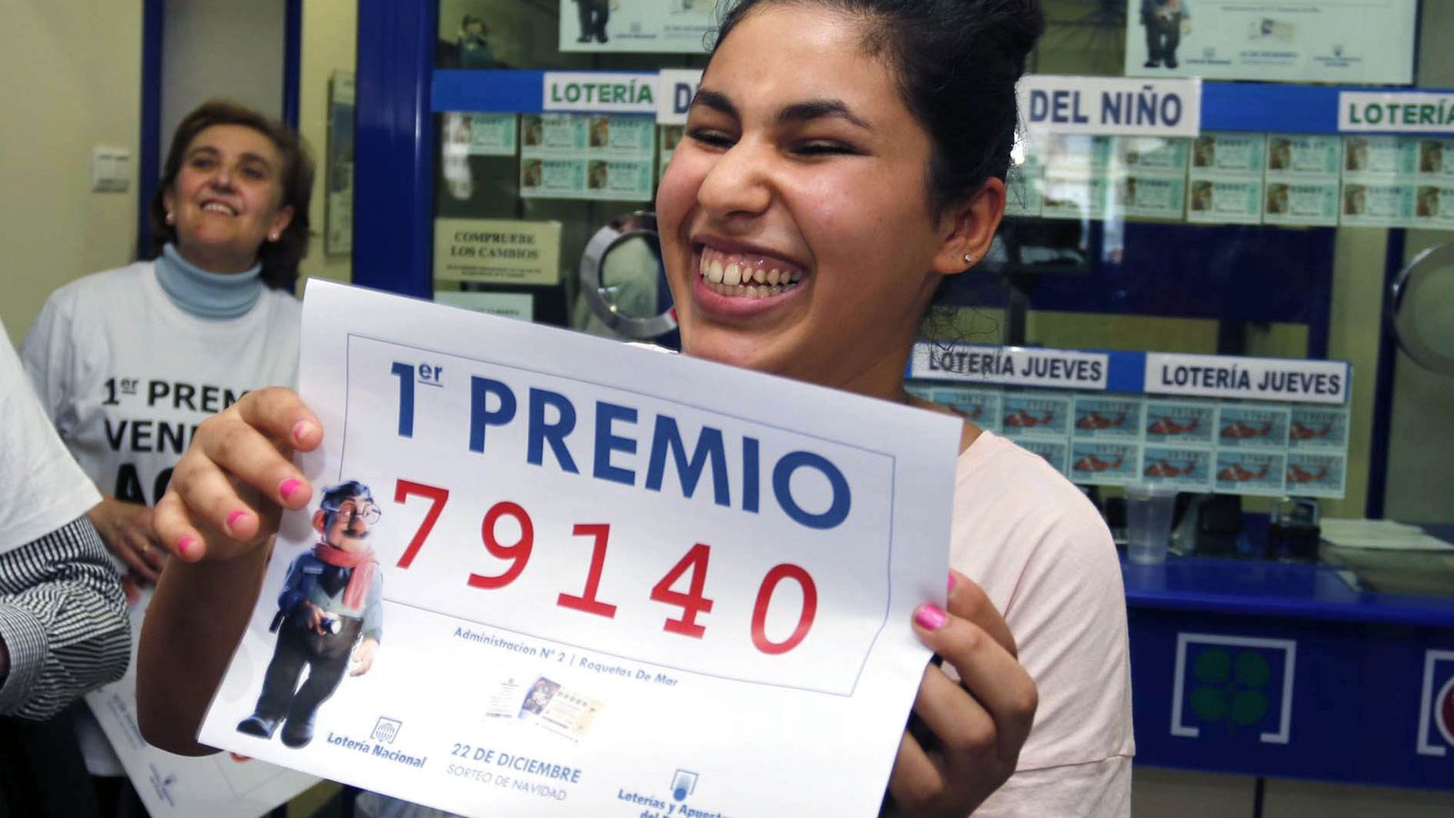 Foto: Una joven sonríe con una copia del primer premio de la Lotería de Navidad vendido en Roquetas de Mar (EFE)