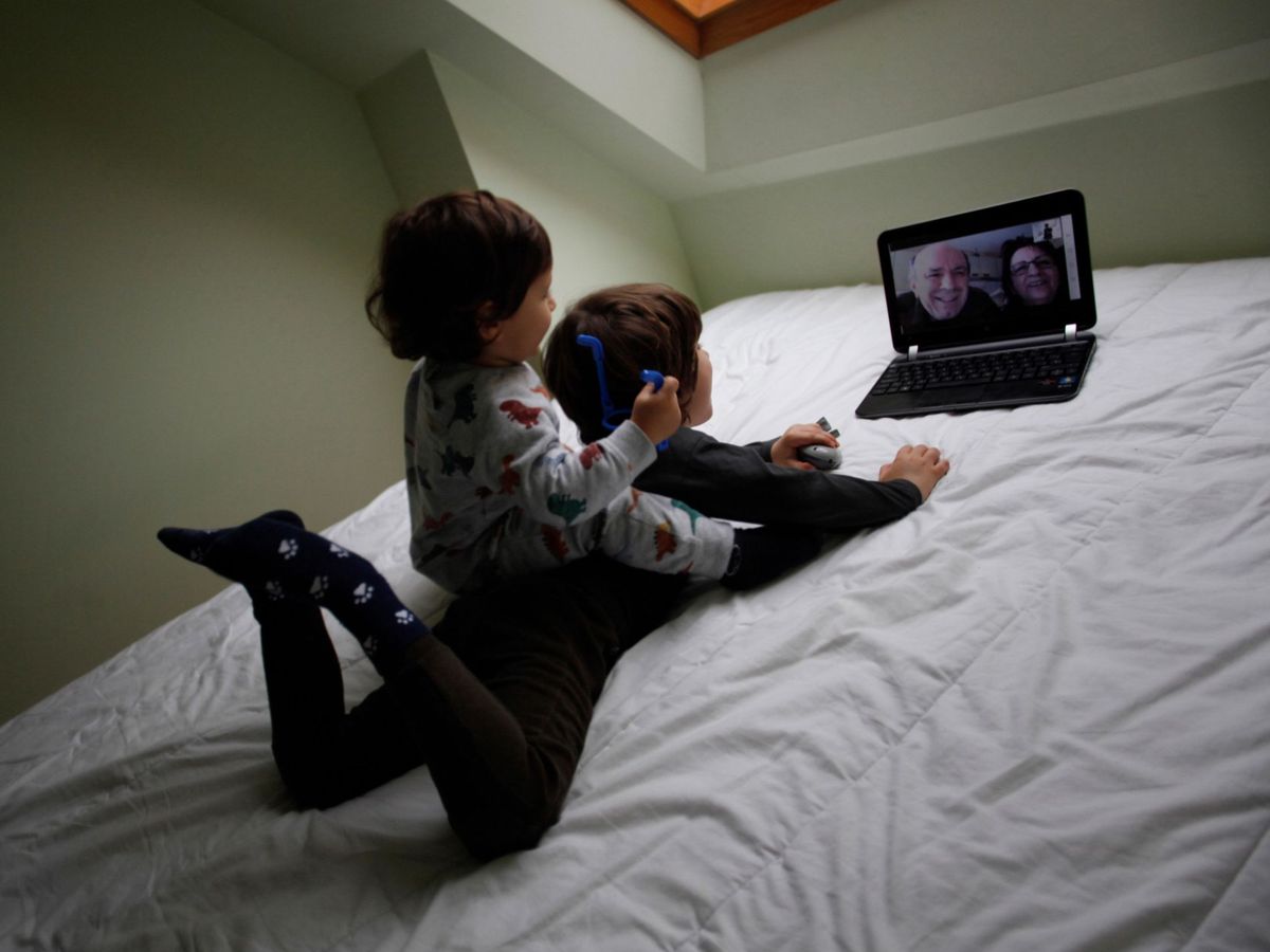 Foto: Dos niños conversan con sus abuelos por medio de una videollamada (EFE)
