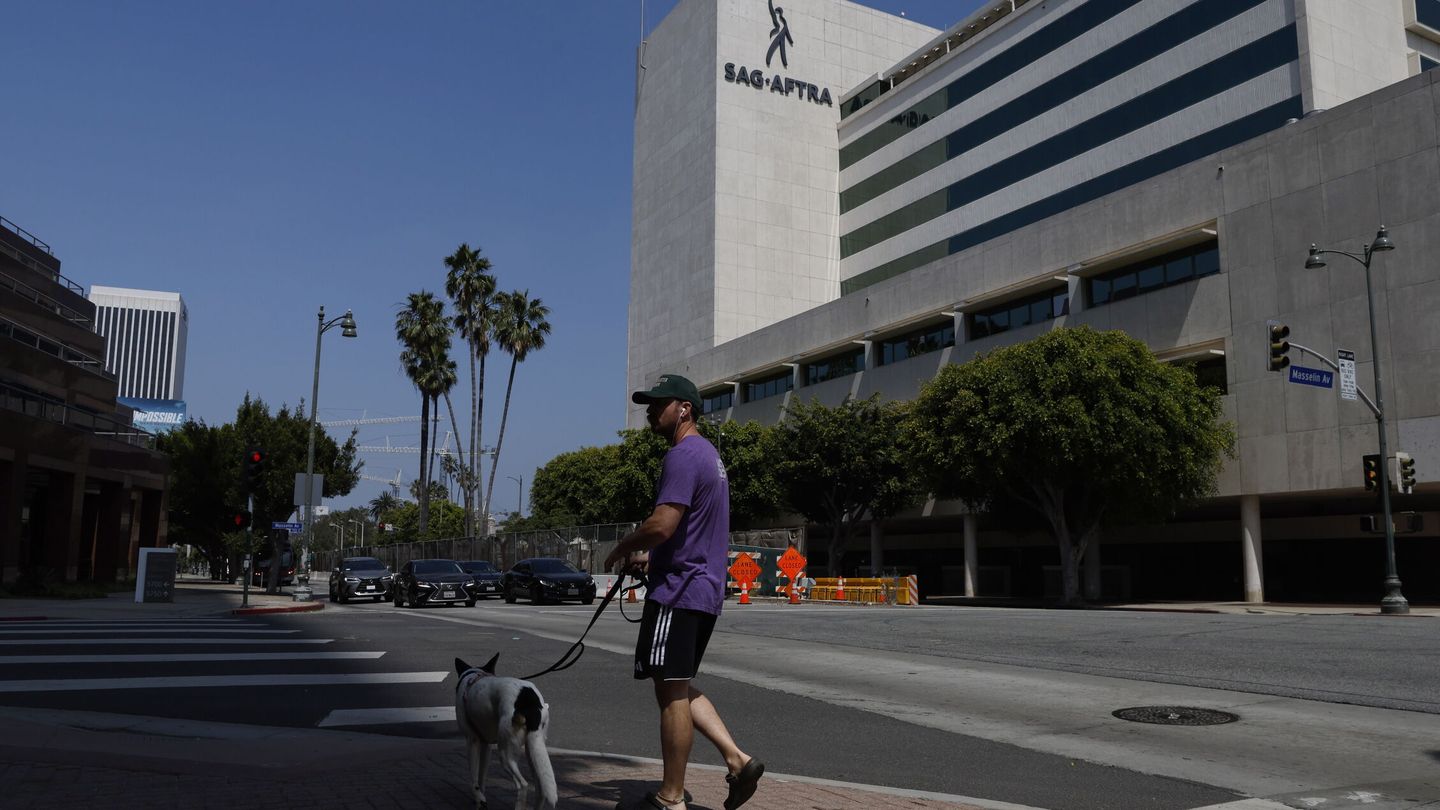 Un hombre pasea a su perro frente a la sede de SAG-AFTRA en Los Ángeles. (EFE/Caroline Brehman) 
