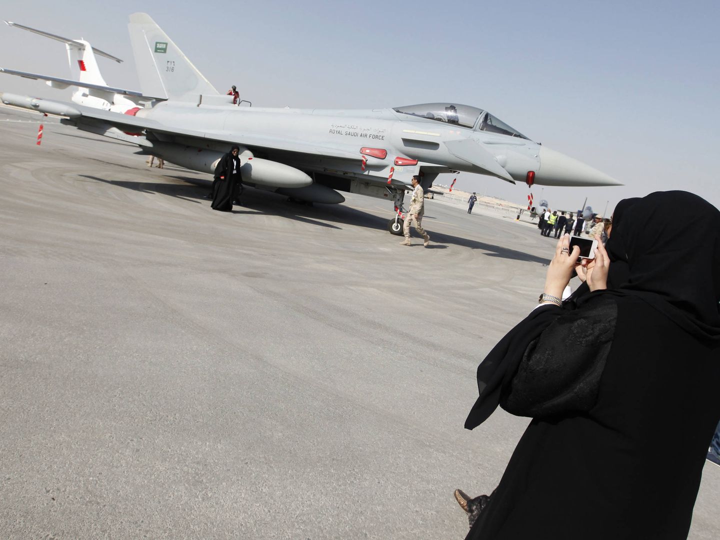 Una mujer fotografía un cazabombardero F16, del ejército saudí. (Reuters)