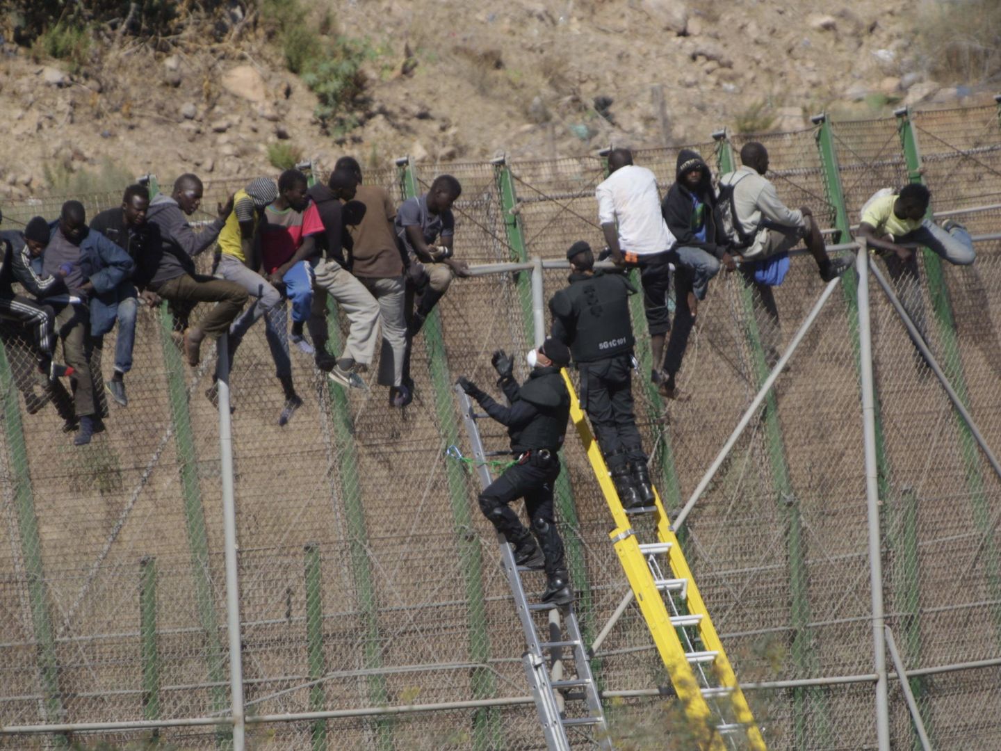 Inmigrantes subidos a la valla de Melilla. (EFE)