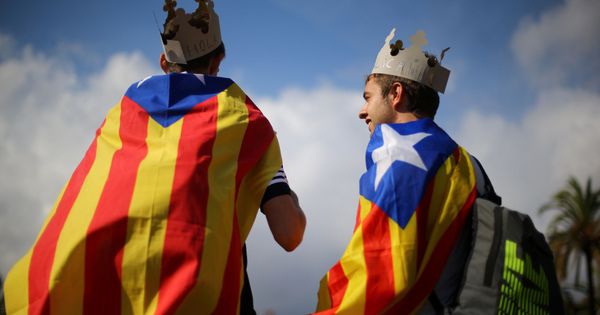 Foto: Dos hombres con coronas de papel y una estelada a la espalda participan en una manifestación a favor de la independencia. (Reuters)