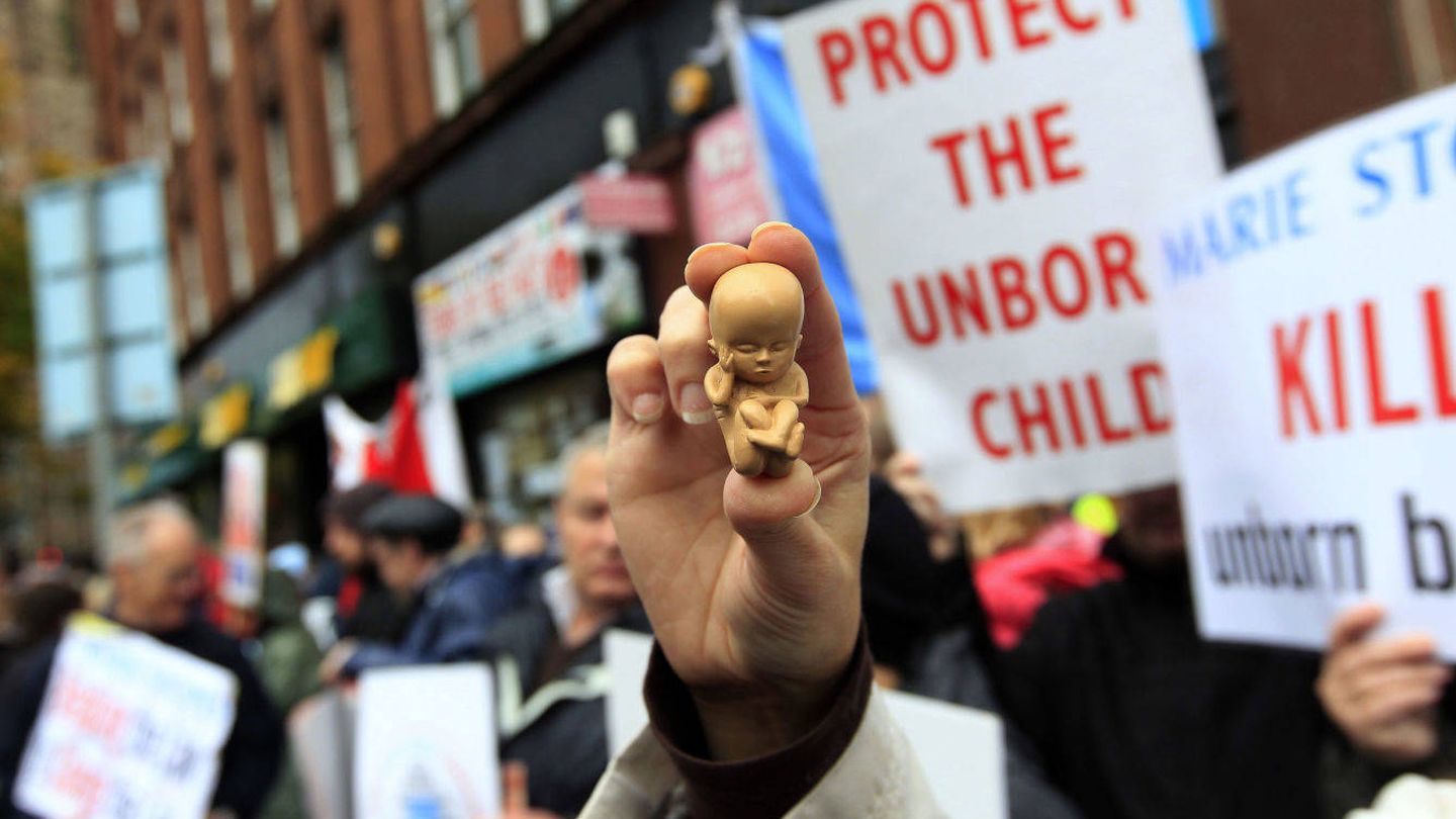 Una manifestante antiabortista sostiene un muñeco de un feto frente a una clínica de Belfast. (Reuters)
