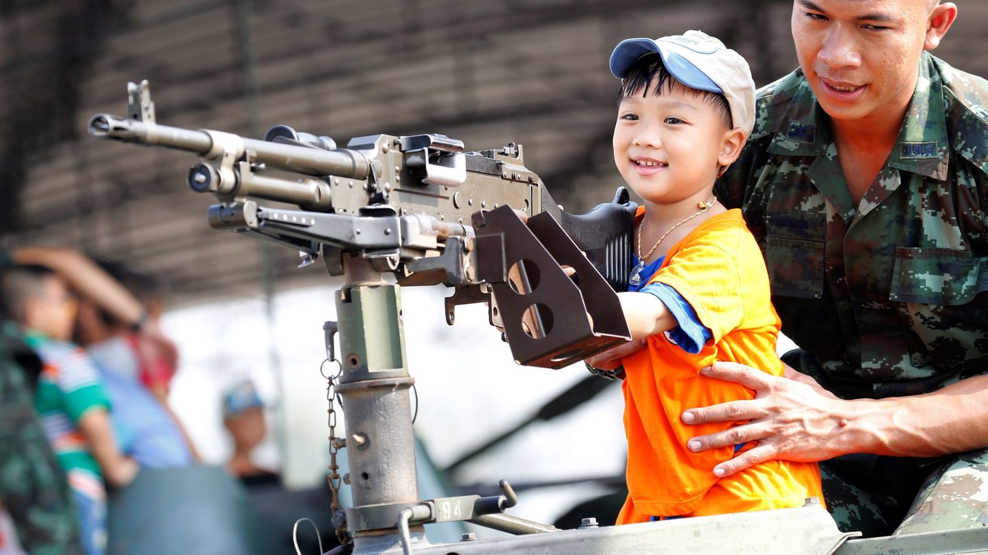 Un niño juega con la ametralladora de un tanque con ayuda de un militar durante el Día Nacional de los Niños en una base militar en Bangkok. (Reuters)