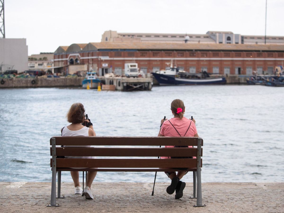 Foto: Dos mujeres descansan en un banco en el puerto de Barcelona. (EFE)