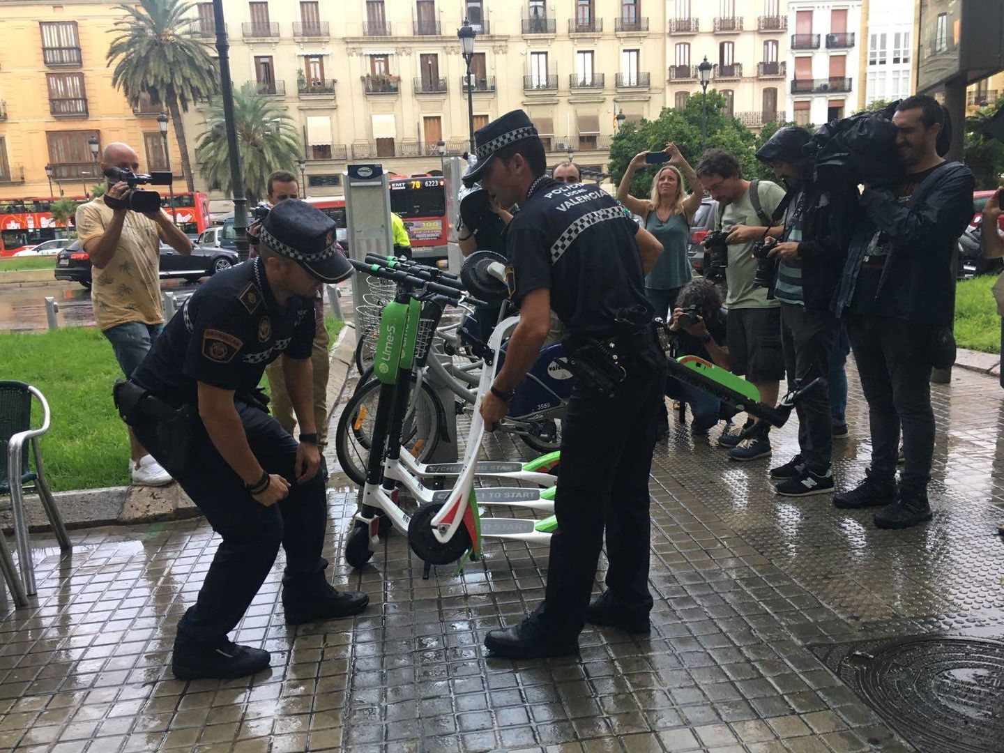 Agentes de la Policía Local de Valencia retiran patinetes de Lime antes los medios de comunicación.