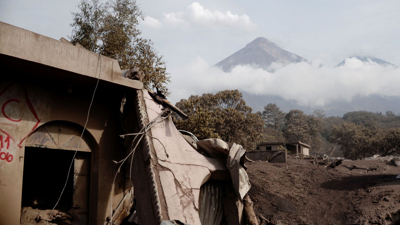 Foto: El Volcán de Fuego visto por detrás de unas viviendas dañadas por la erupción en El Rodeo, el 6 de junio de 2018. (Reuters)