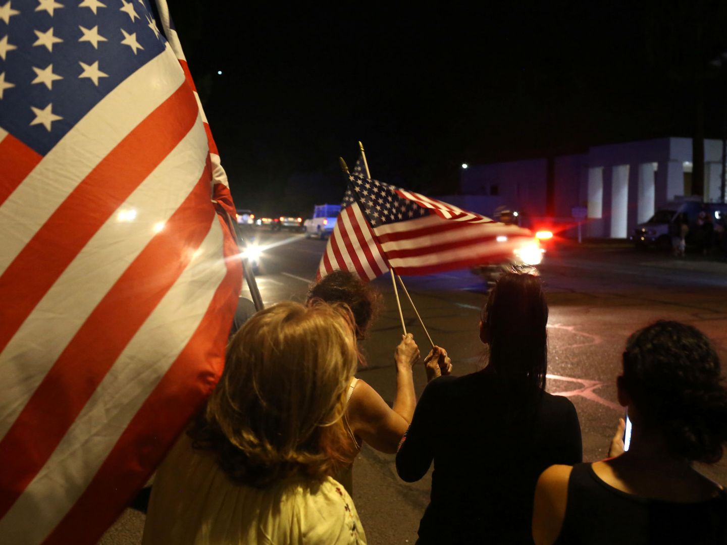 Decenas de personas han salido a la calle con banderas al paso del coche fúnebre con el cuerpo de McCain. (Reuters)