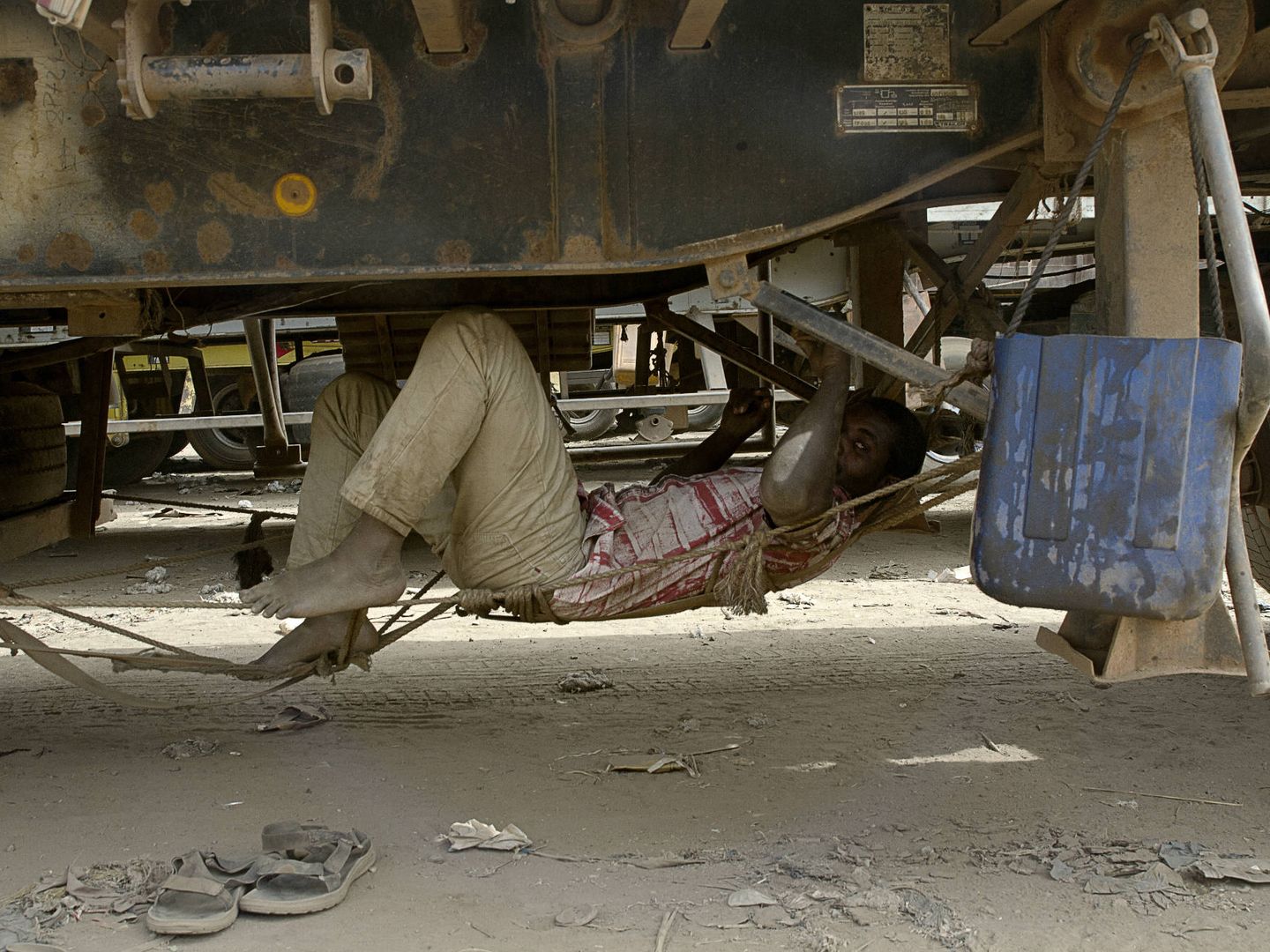 Un conductor descansa en una hamaca improvisada bajo su camión. (K. Gómez)