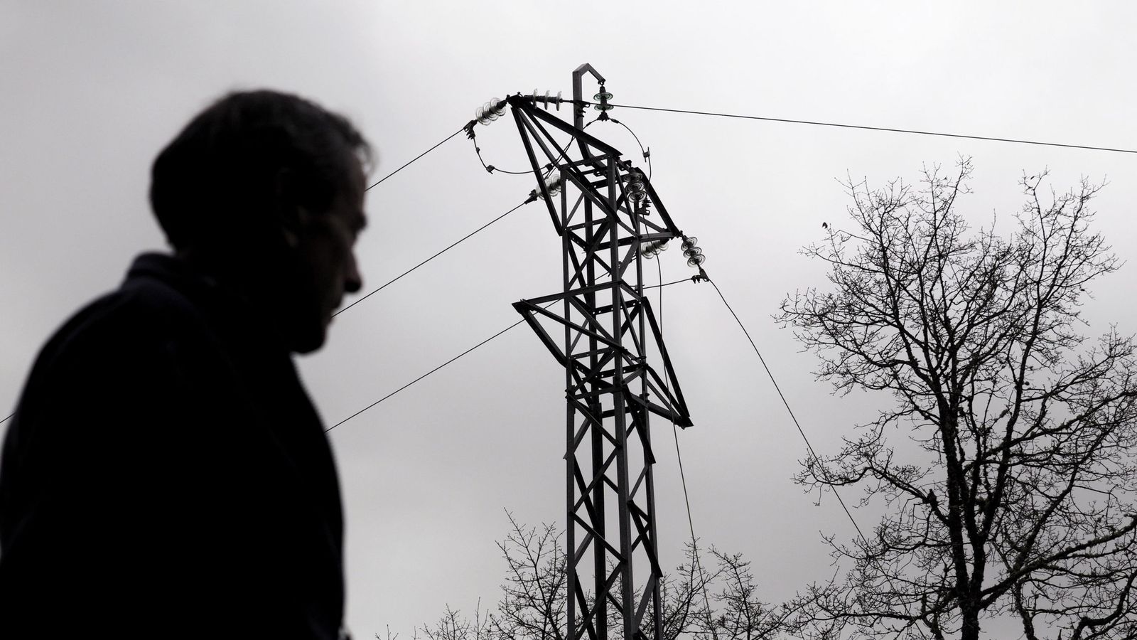 Foto: Un hombre pasa junto a una torreta con el tendido eléctrico caído por el temporal. (EFE)