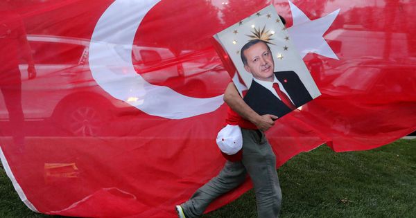 Foto: Un votante de Erdogan sostiene una imagen del presidente ante una bandera turca, en Estambul. (Reuters)