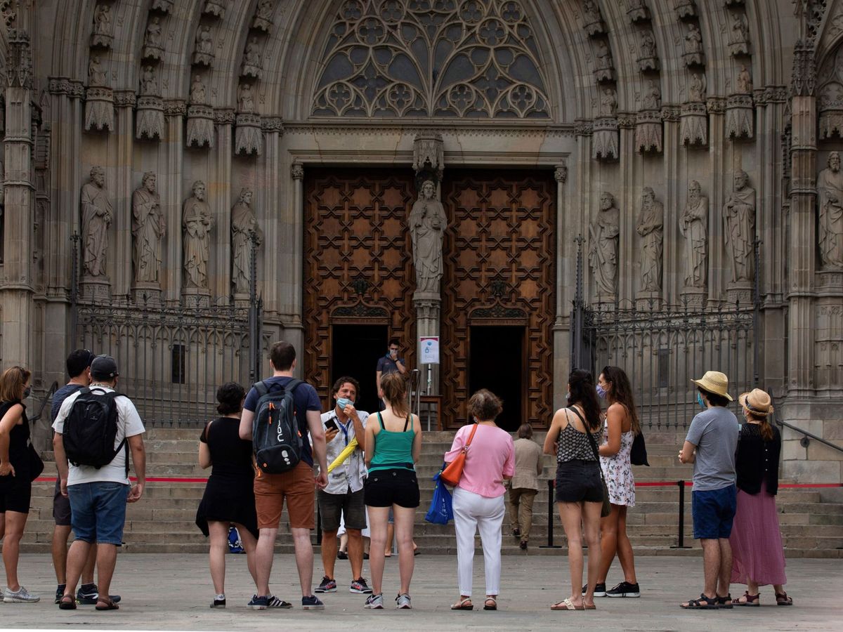 Foto:  Un grupo de turistas atiende a las explicaciones de su guía, ante la catedral de Barcelona. (EFE/Enric Fontcuberta) 