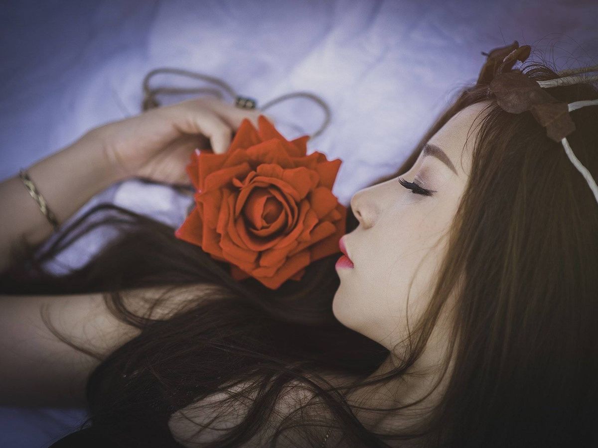 Foto: Una mujer huele una rosa mientras duerme. Foto: Pixabay