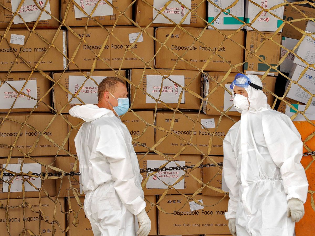Foto: Operarios con traje de protección se disponen a comenzar la descarga de las 65 toneladas de material sanitario que la Generalitat ha comprado a China. (EFE)