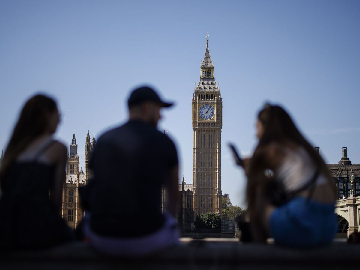 Foto: La gente se sienta en el Southbank con el Palacio de Westminster de fondo. (EFE / Tolga Akmen)