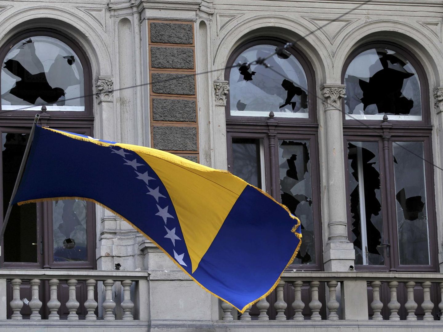 Una bandera de Bosnia-Herzegovina ondea frente a un edificio dañado en Sarajevo. (Reuters)