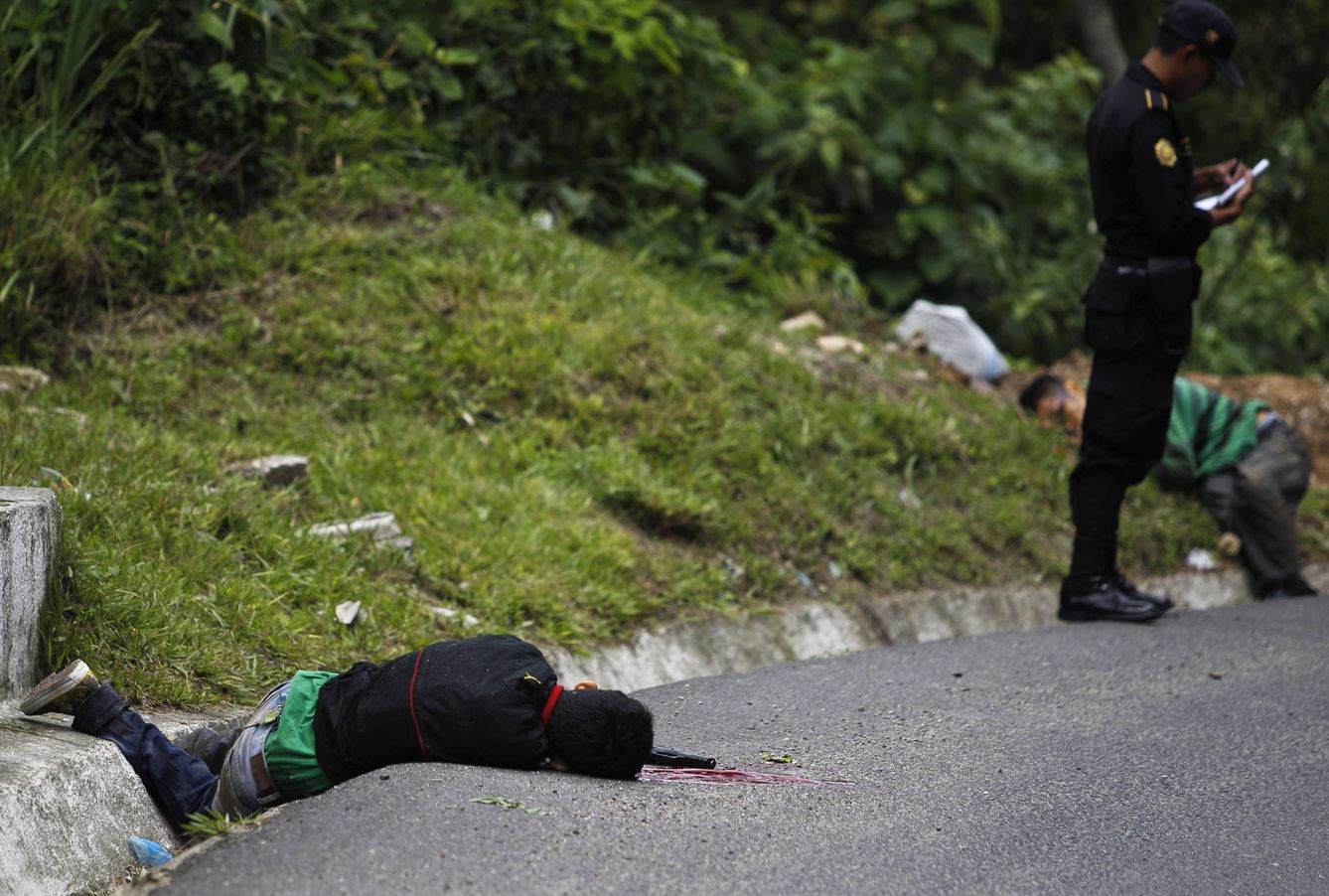 Un agente junto a los cadáveres de dos supuestos pandilleros en Chinautla, en las afueras de Ciudad de Guatemala. (Reuters)