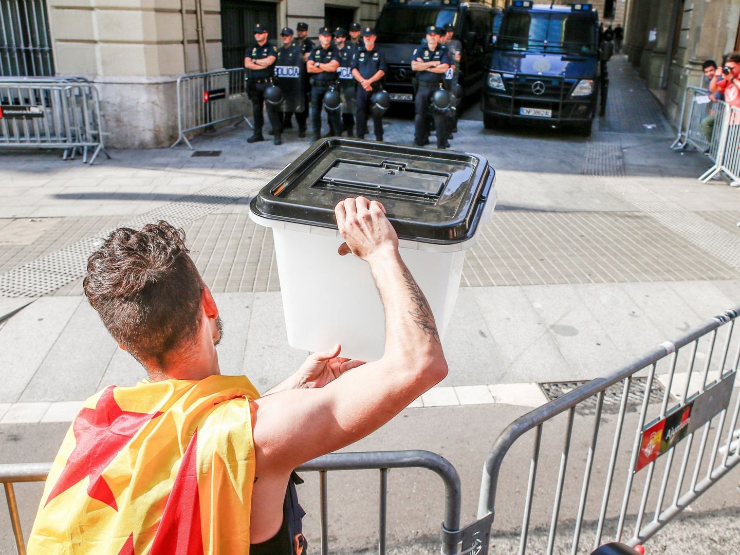 Un joven muestra una urna empleada el 1-O a los policías apostados en la Via Laietana, en Barcelona. (EFE)