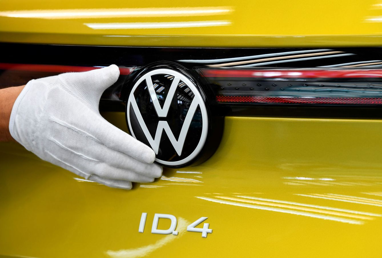 Empleado revisando el logo de Volkswagen en un coche ID.4 (Reuters)