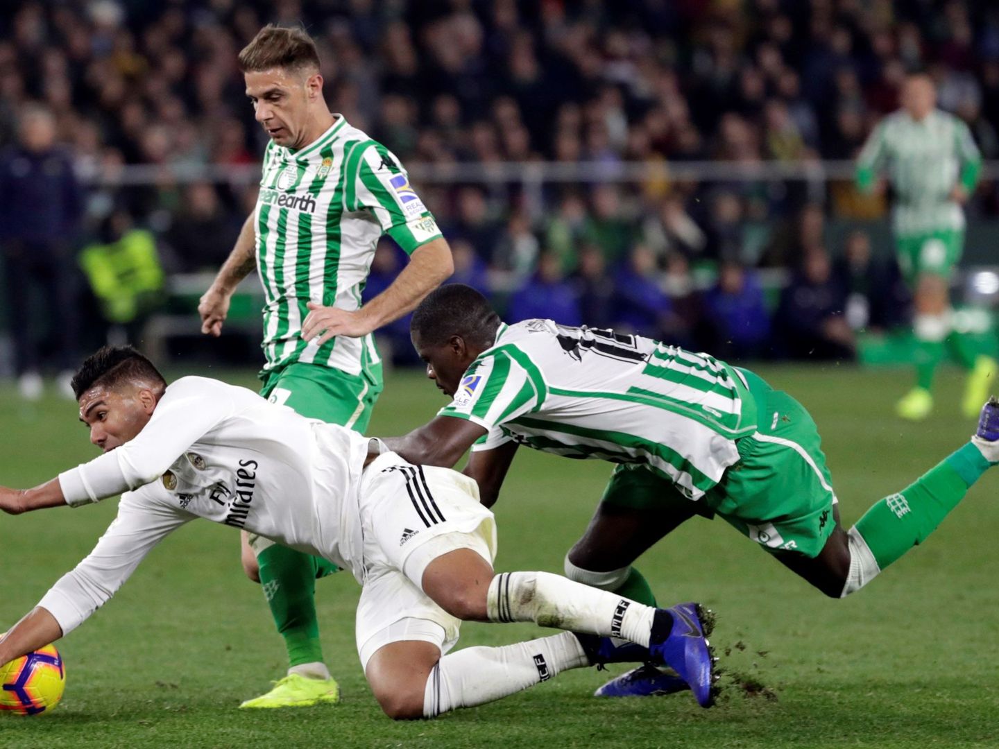 Casemiro (i), cae ante los jugadores del Real Betis, Joaquín Sánchez y el portugués William Carvalho, durante un partido. (EFE)