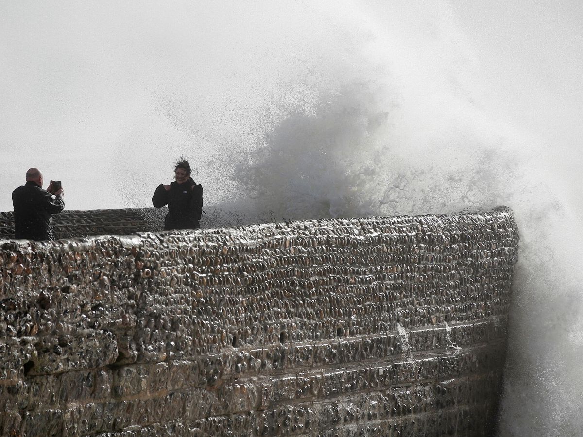 Foto: Personas sacándose fotos de las olas rompiendo durante la tormenta Eunice, en Brighton. (Reuters)