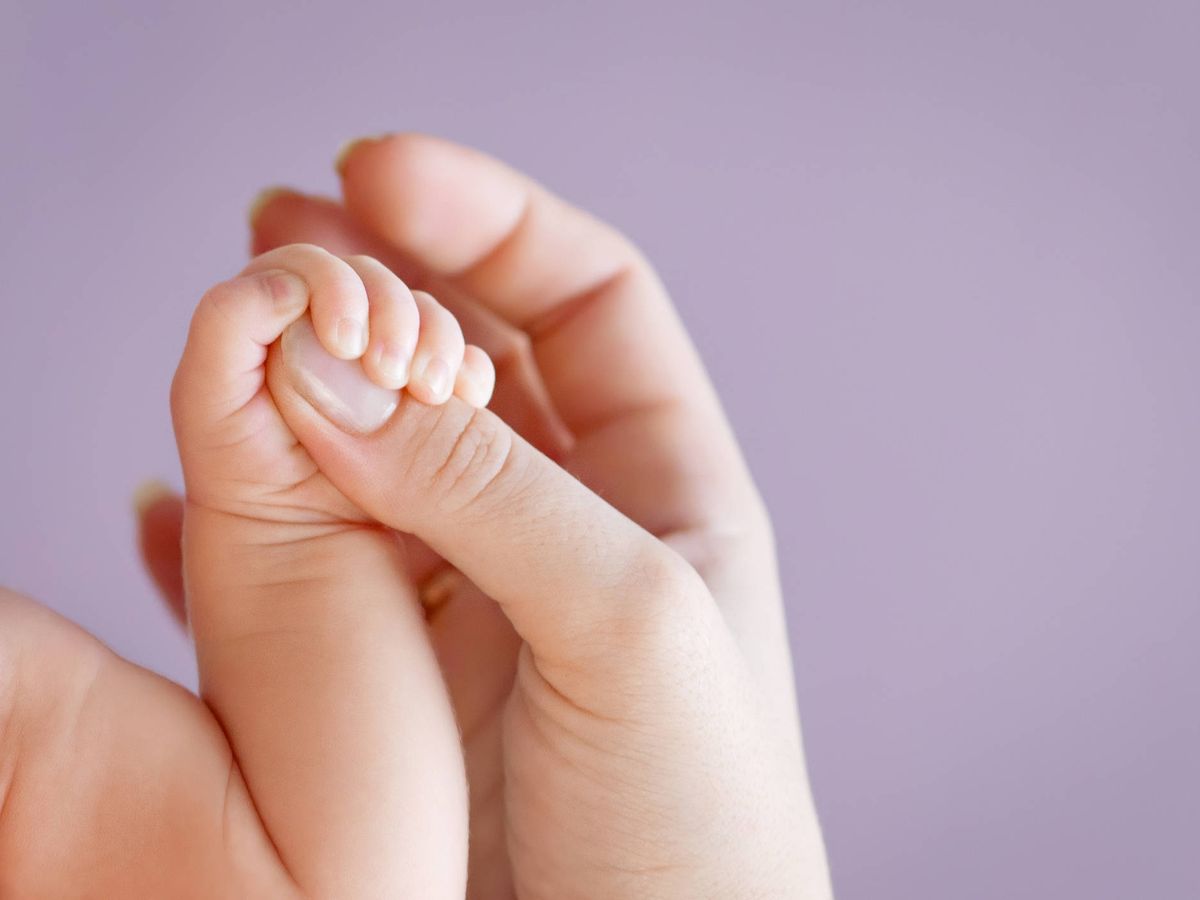 Foto: Un adulto sostiene la mano de un bebé. (iStock)