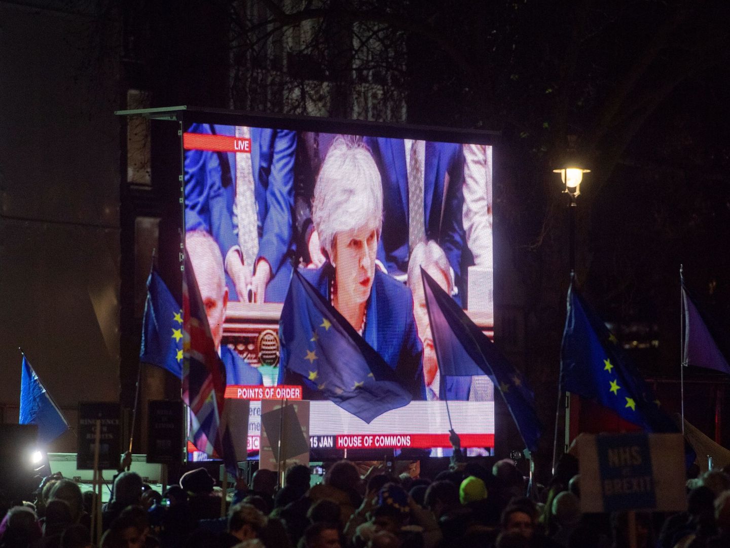 Decenas de personas agitan banderas de la Unión Europea mientras miran en una pantalla gigante la intervención de Theresa May durante la votación del Brexit en Londres. (EFE)