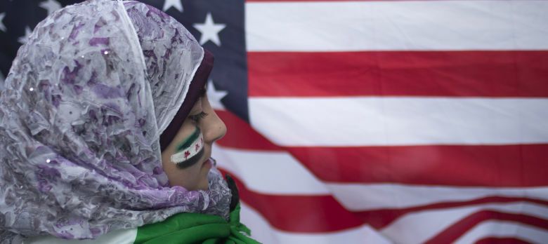 Displaced Syrian girl Malek Al Rifai stands in front of a U.S. flag while taking part in a protest in front of the United Nations building in New York