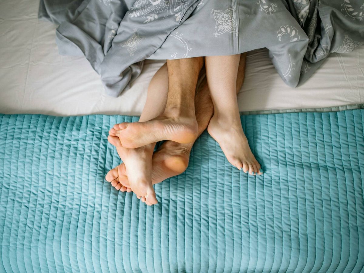 Foto: Dos piernas entrelazadas en la cama. (Pexels)