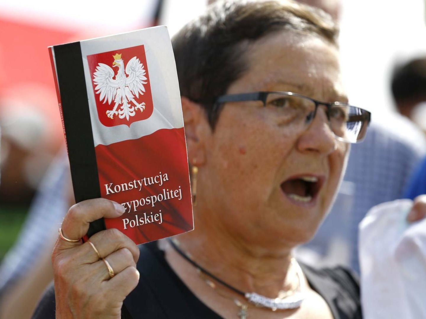Una mujer enarbola una copia de la constitución de Polonia durante una protesta frente a la sede del Partido Ley y Justicia en Varsovia. (Reuters)