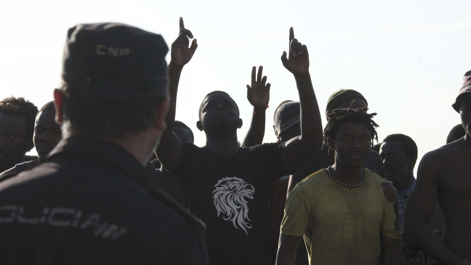 Foto: Agentes de la Policía Nacional frente a inmigrantes, en Ceuta. (EFE)