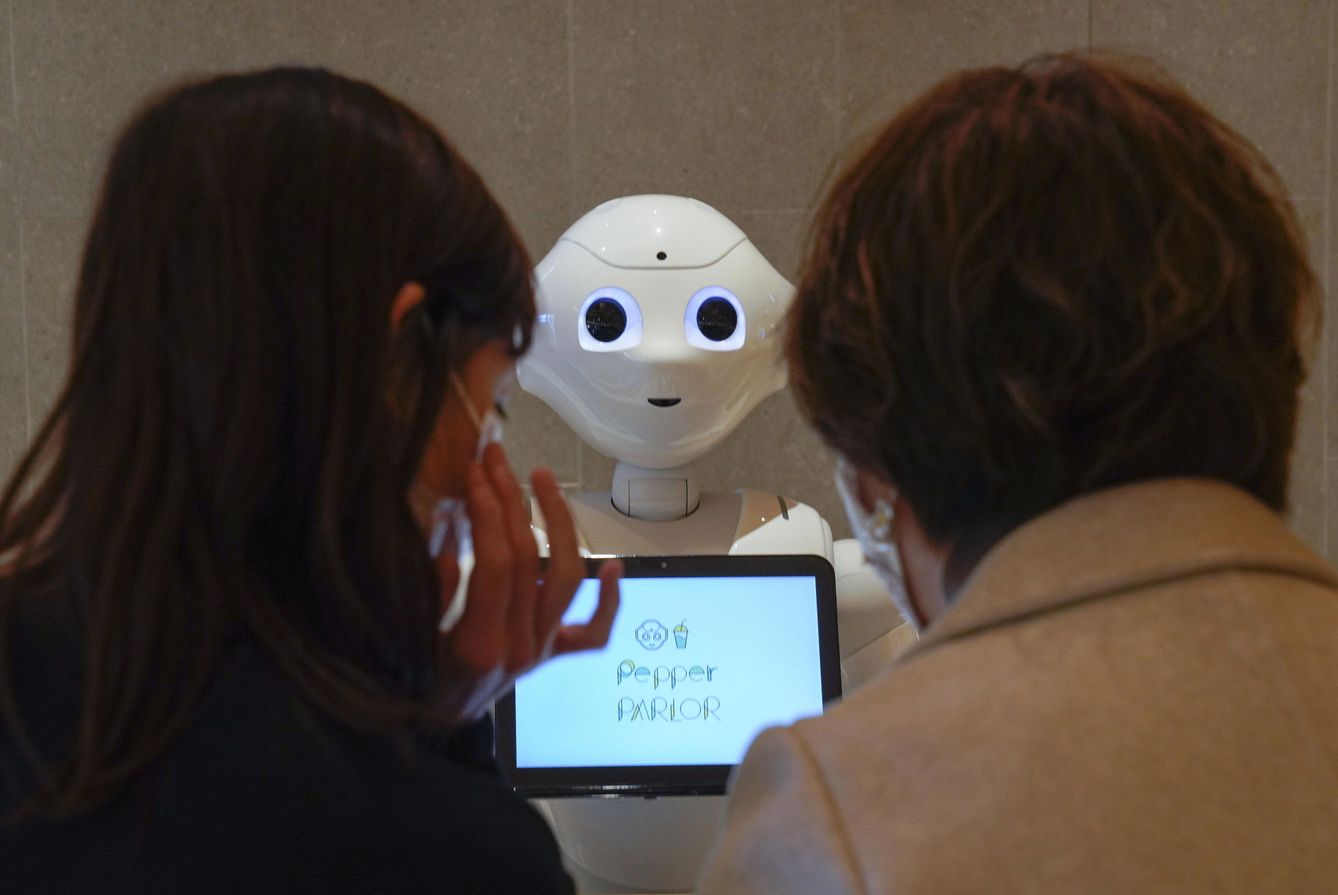 Dos personas hablan con un robot. (Reuters)