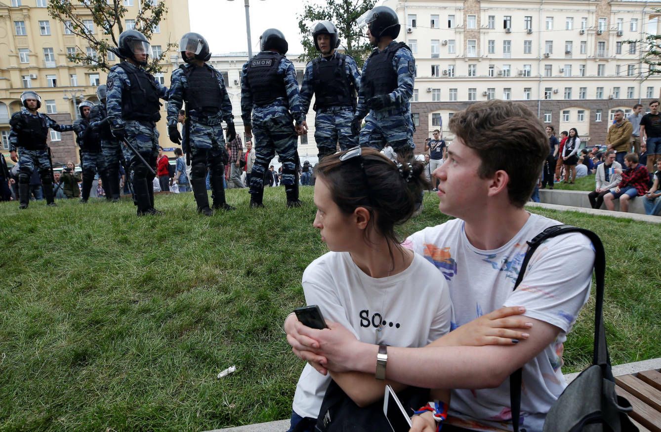 Dos jóvenes miran a unos agentes antidisturbios durante una protesta anticorrupción en Moscú, el 12 de junio de 2017. (Reuters)