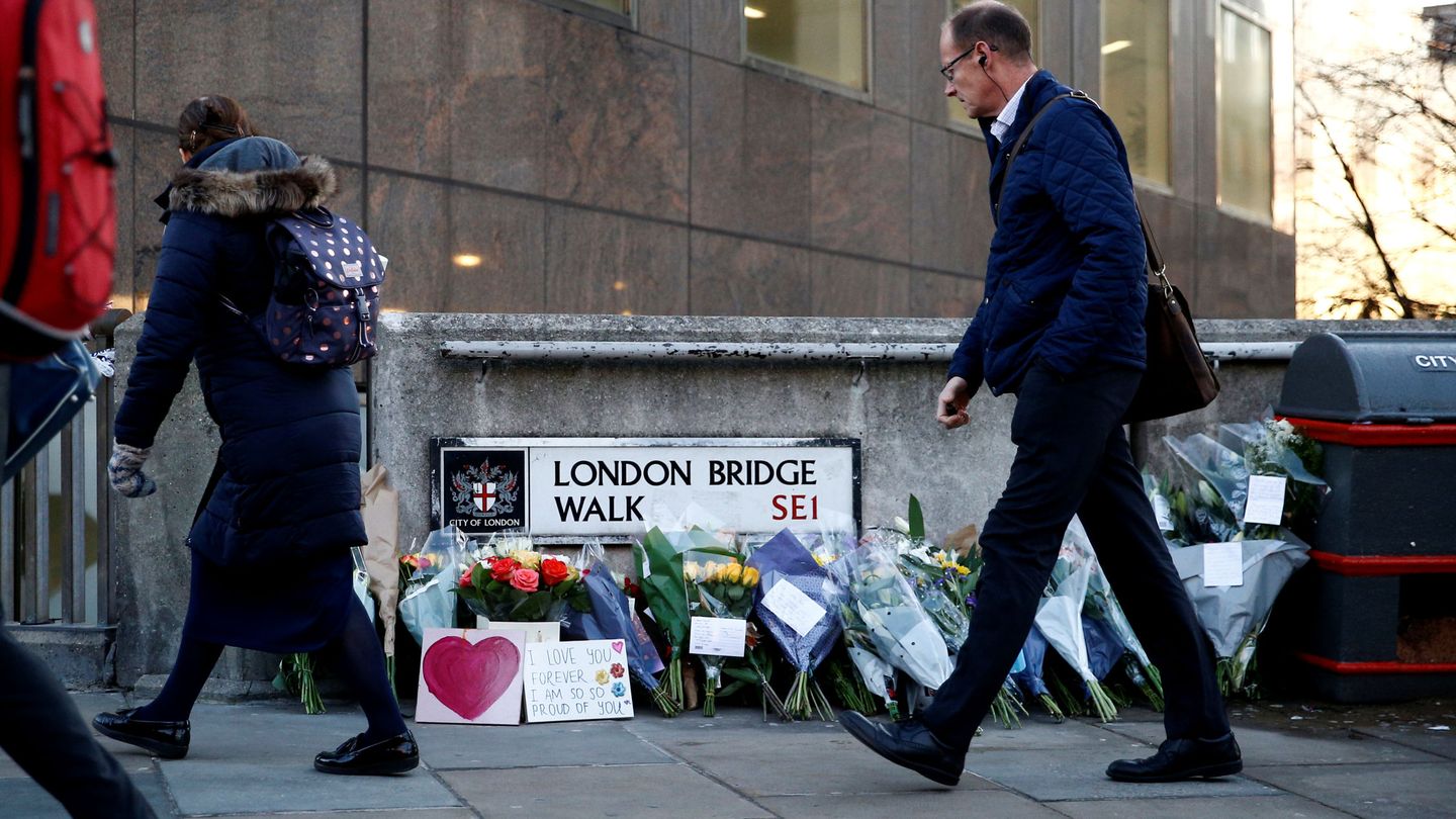 Varios viandantes pasean junto al homenaje improvisado por las víctimas del ataque terrorista en London Bridge. (Reuters)