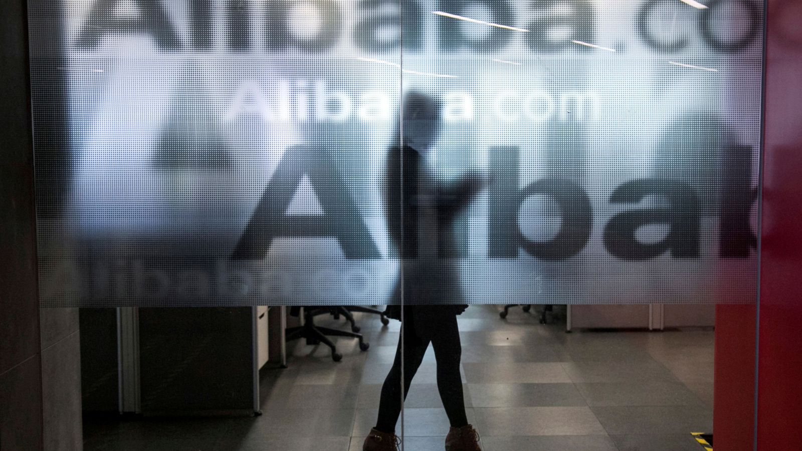 Foto: Una trabajadora, detrás de un logotipo de Alibaba en las oficinas de la compañía en Hangzhou. (Reuters)
