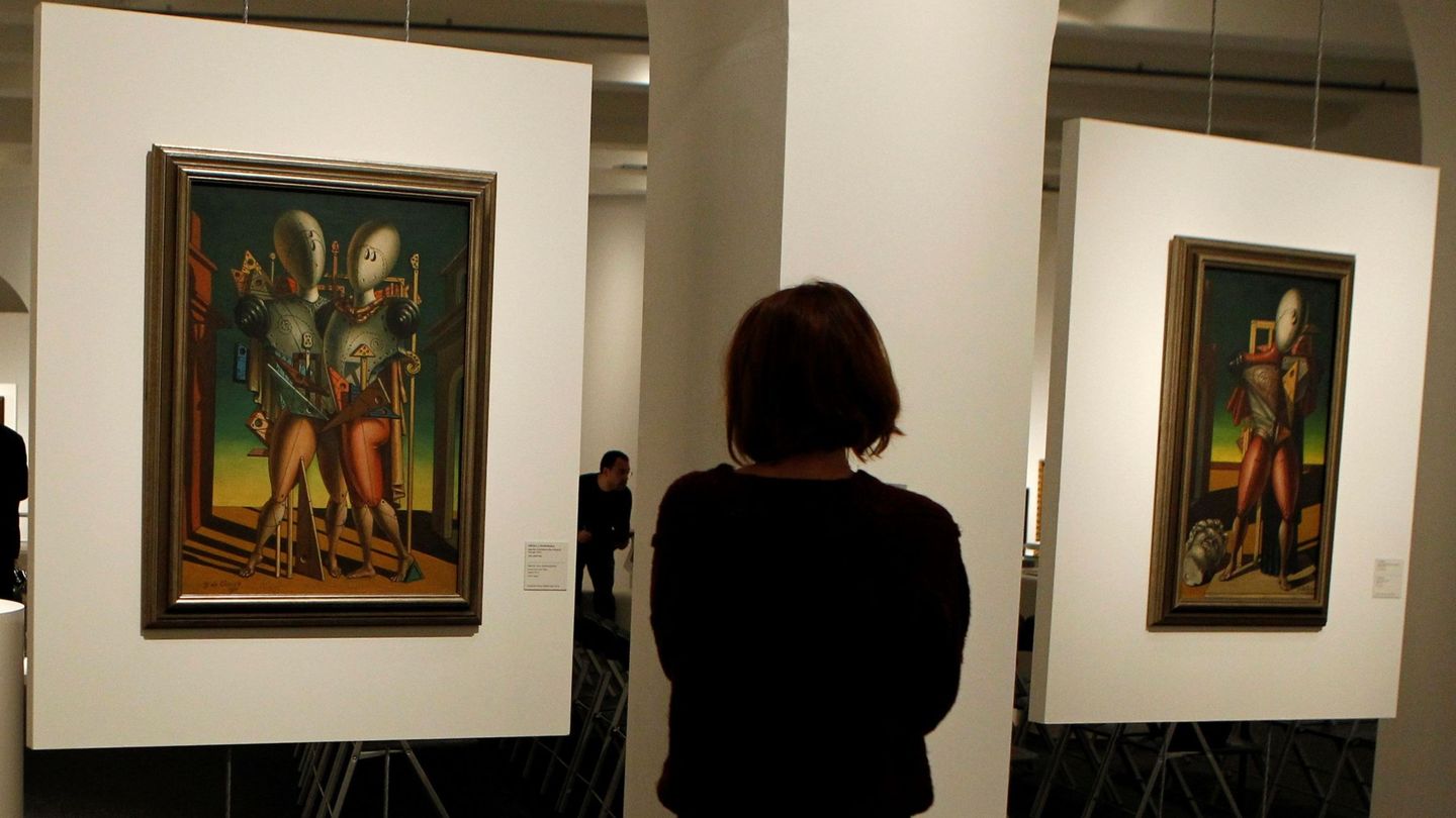 Una mujer observa los cuadros 'Ettore e Andromaca' y 'Il Trovatore', de Giorgio de Chirico, que formna parte de la exposición de CaixaForum Madrid. (EFE)