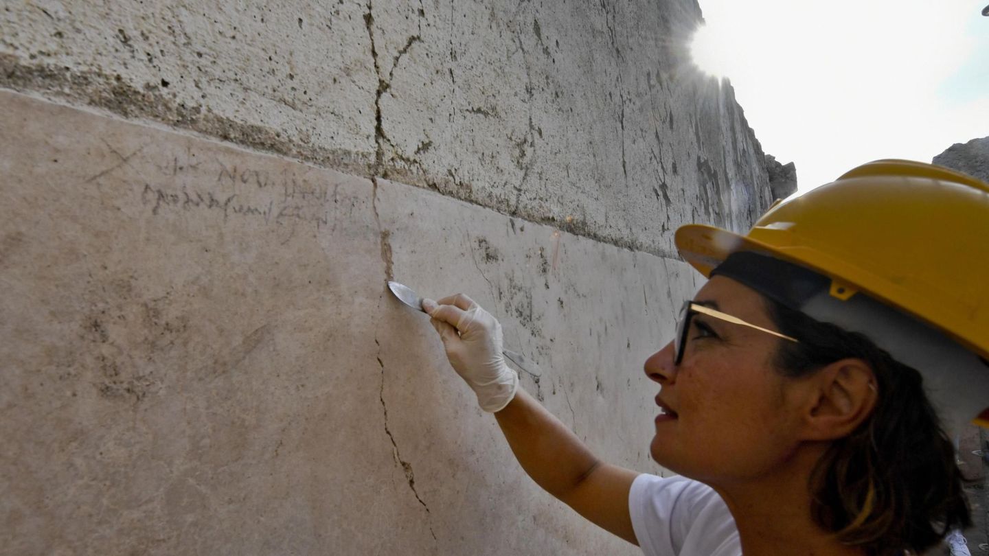 Una arqueóloga señala la inscripción de una pared encontrada en una excavación en Pompeya que acaba finalmente con la duda histórica sobre la fecha de la erupción del Vesubio que sepultó a la ciudad (EFE)