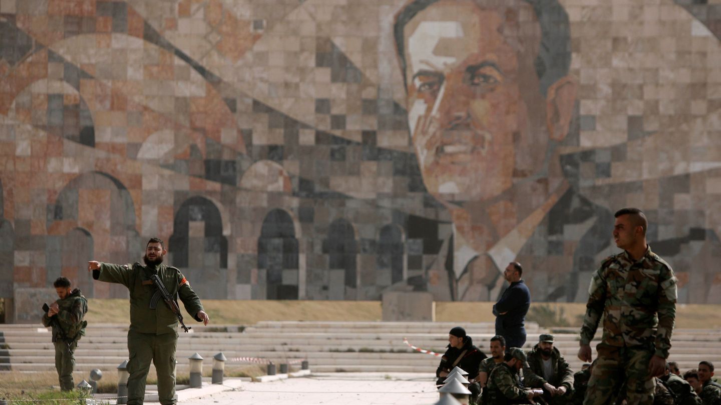Soldados del ejército sirio frente a un mural de Hazef al Asad, padre del actual presidente, en Harasta, a finales de marzo. (Reuters)