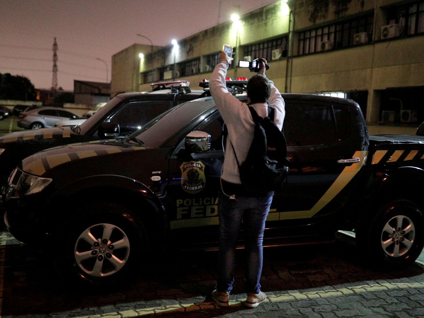 Un cámara, junto a los coches de la Policía Federal en el Aeropuerto de Guarulhos. (Reuters)