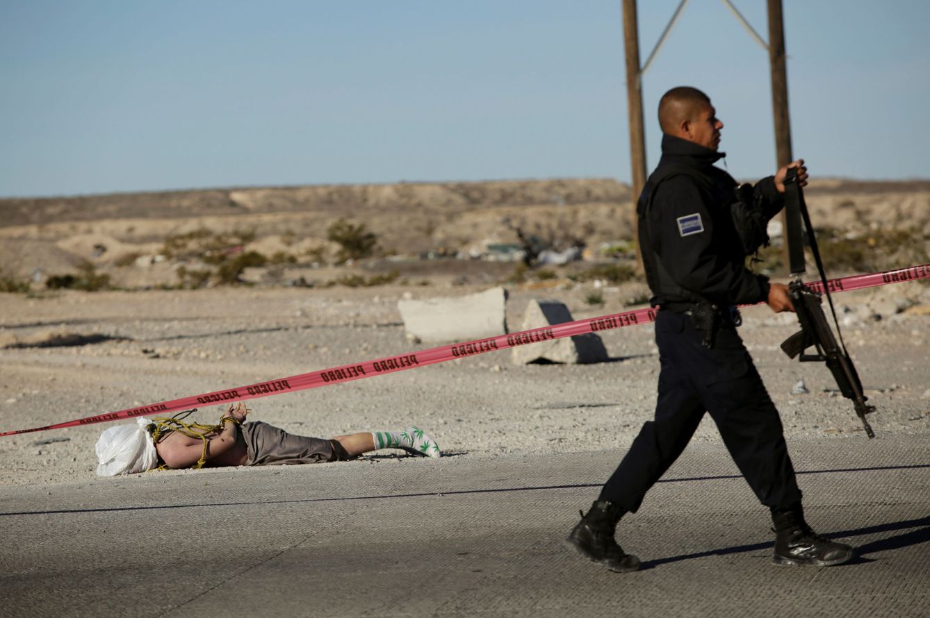 Un policía pasa ante un cadáver en las afueras de Ciudad Juárez. (Reuters) 