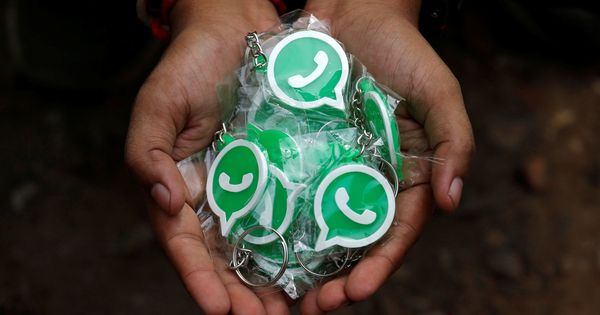 Foto: Una persona sostiene llaveros con el símbolo de WhatsApp. (Reuters)