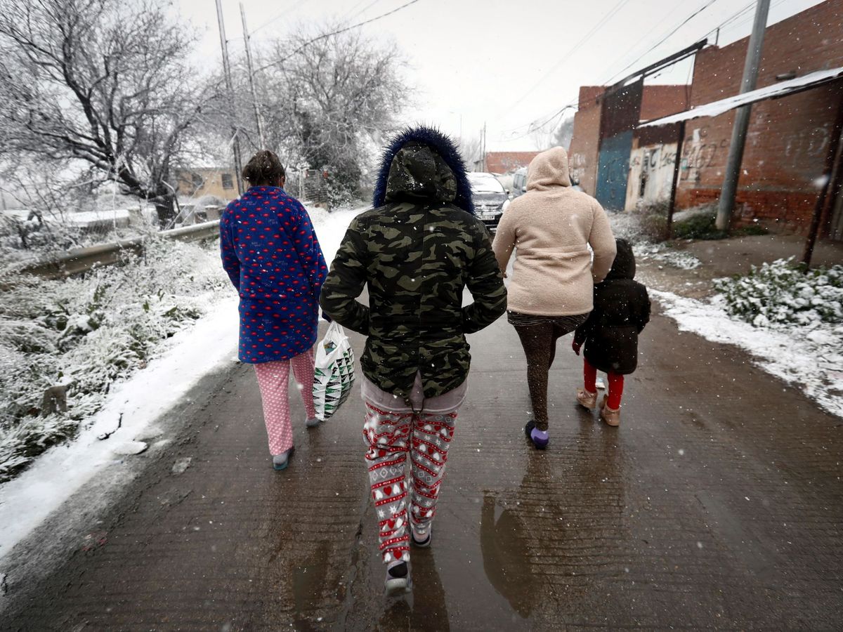 Foto: Varios residentes de la Cañada Real caminan bajo la nieve este jueves. (EFE)