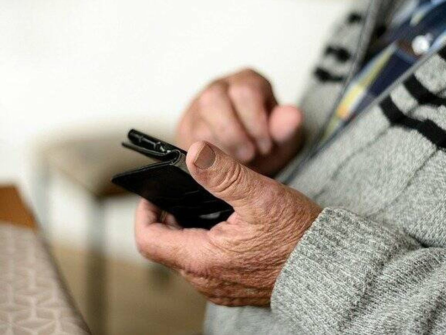 Una persona mayor utilizando un teléfono móvil. 