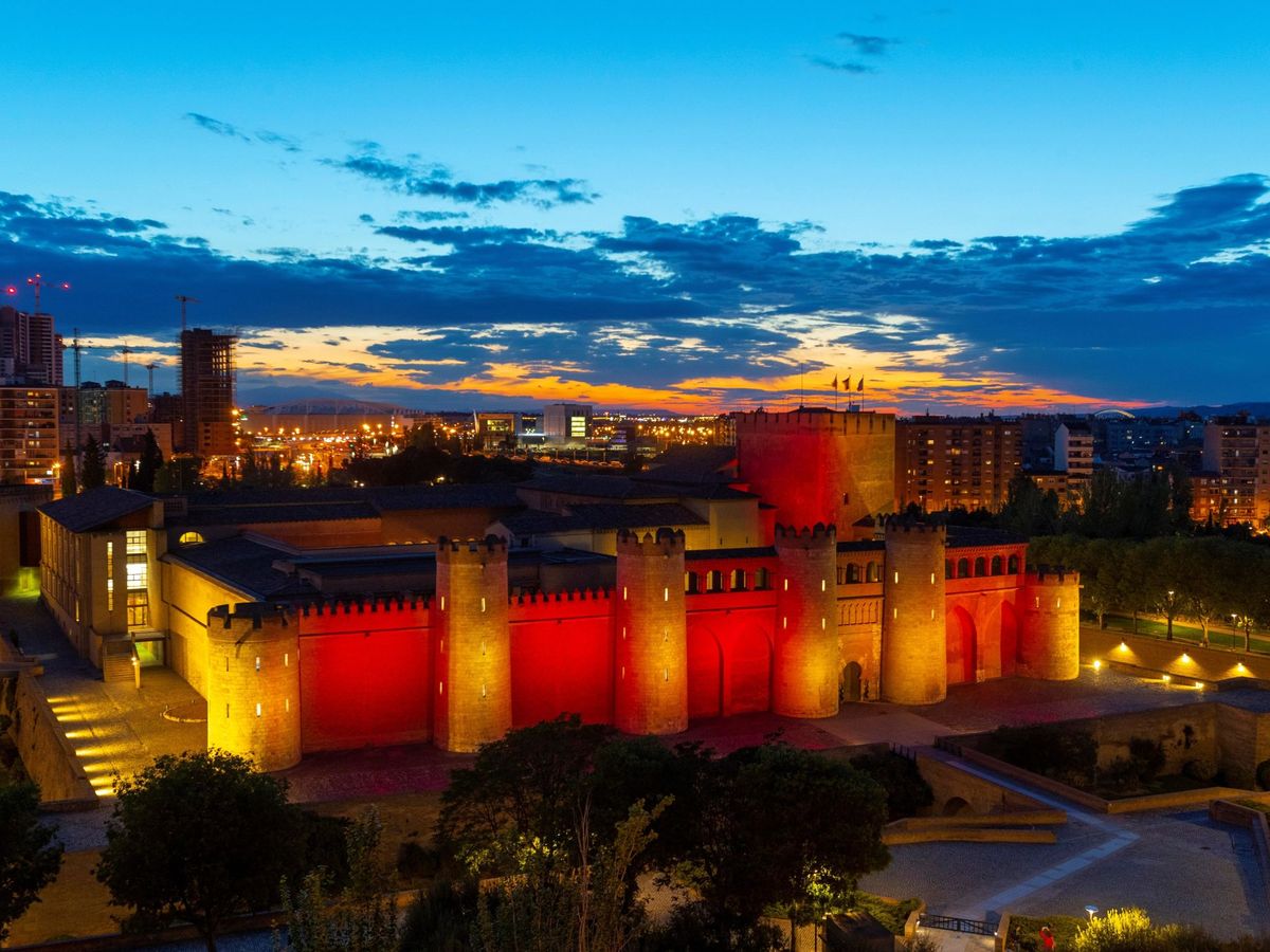 Foto: El palacio de La Aljafería, segundo edificio más visitado de Zaragoza, ilumina sus murallas con los colores de la bandera de Aragón el día de San Jorge, patrón de la Comunidad Autónoma. (EFE/Javier Belver)