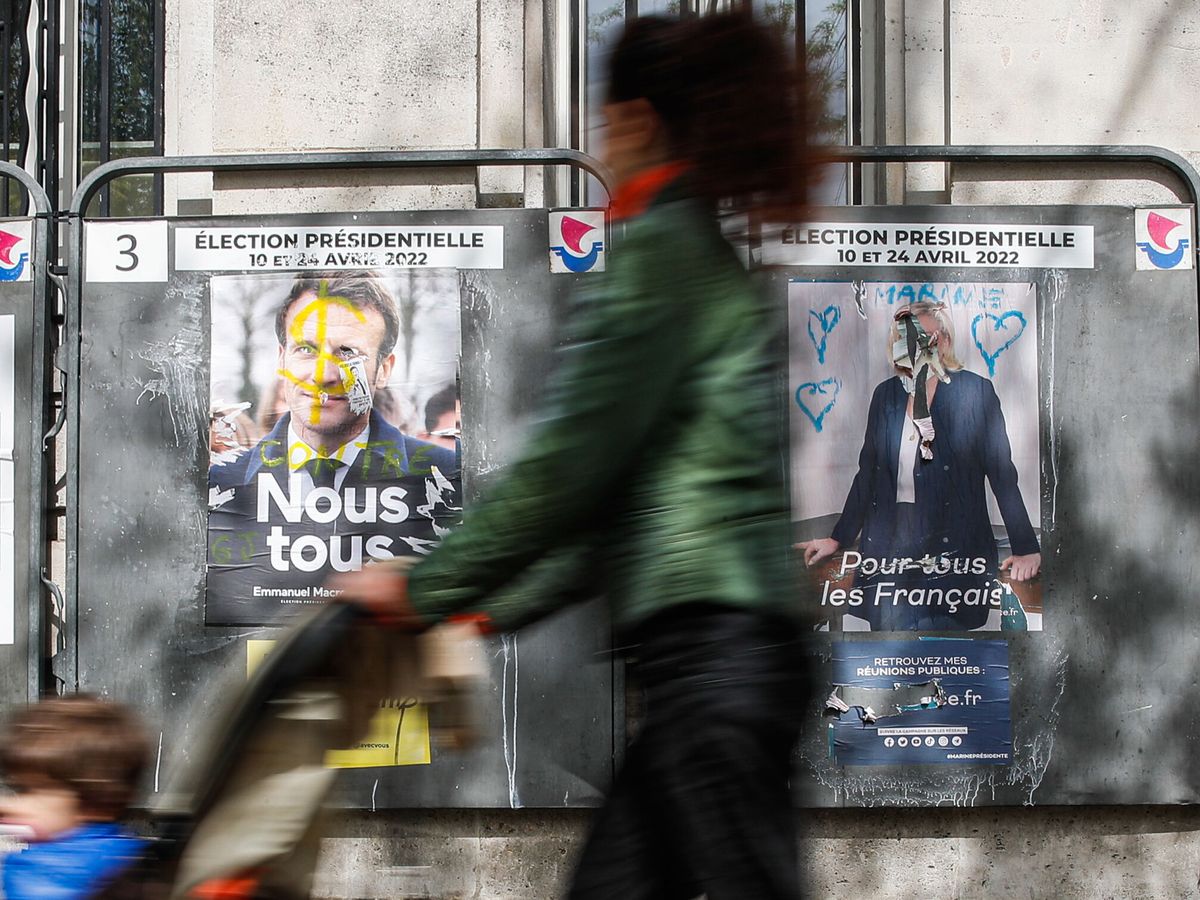 Foto: Una mujer, junto a carteles electorales de Macron y Le Pen, en París. (EFE/Mohamed Badra) 