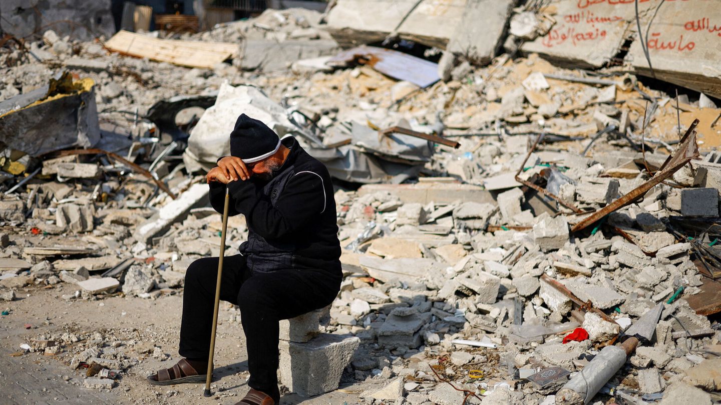 Ziad Mansour, a neighbour of the Abu Aweidah family, sits next to writing painted on a wall amid the rubble of the family's house, which was destroyed in a deadly Israeli strike amid the ongoing conflict between Israel and the Palestinian Islamist group Hamas, in Rafah, Gaza Strip, January 9, 2024. REUTERS Mohammed Salem