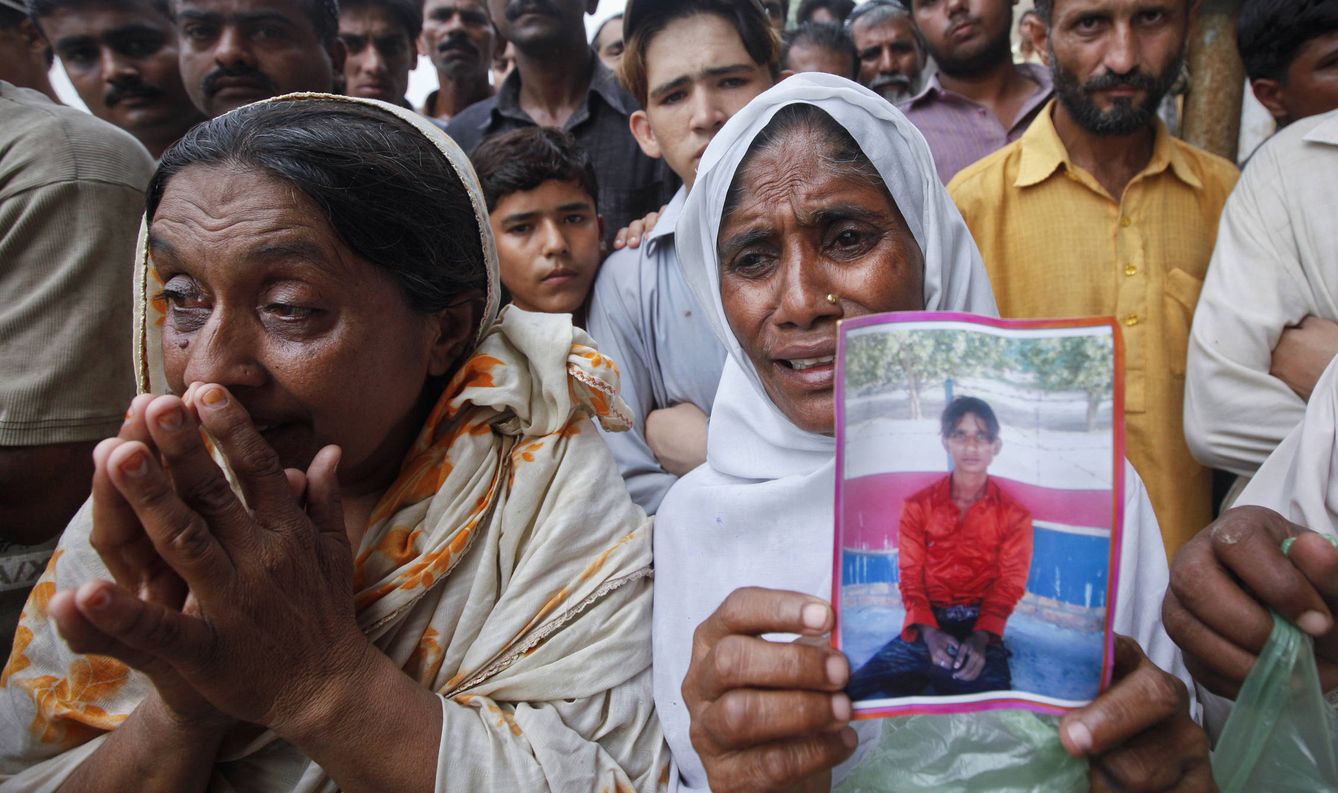 Una mujer sostiene la foto de su hijo mientras los familiares esperan noticias sobre los muertos en el incendio, el 12 de septiembre de 2012. (Reuters)