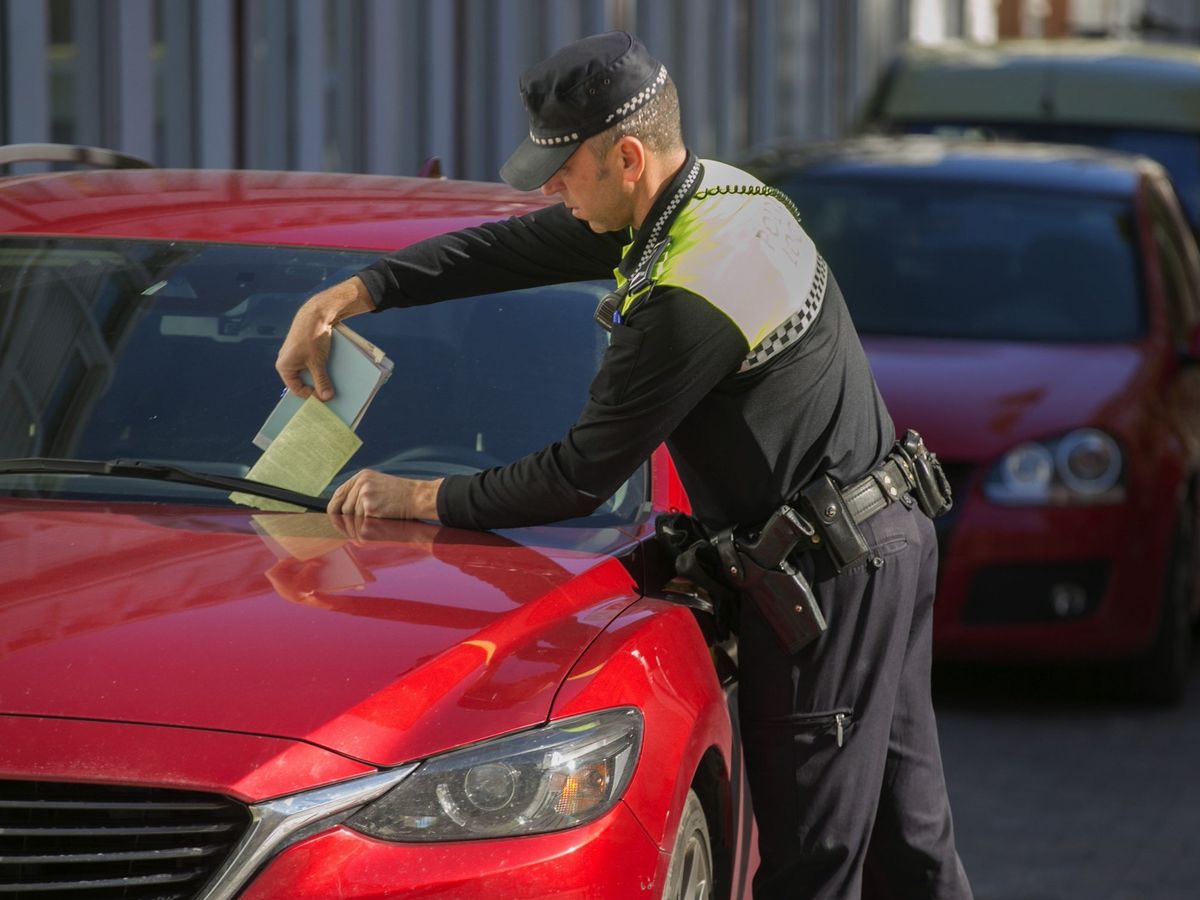 Foto: Un agente de Policía pone una multa en un coche en Vitoria. (EFE)